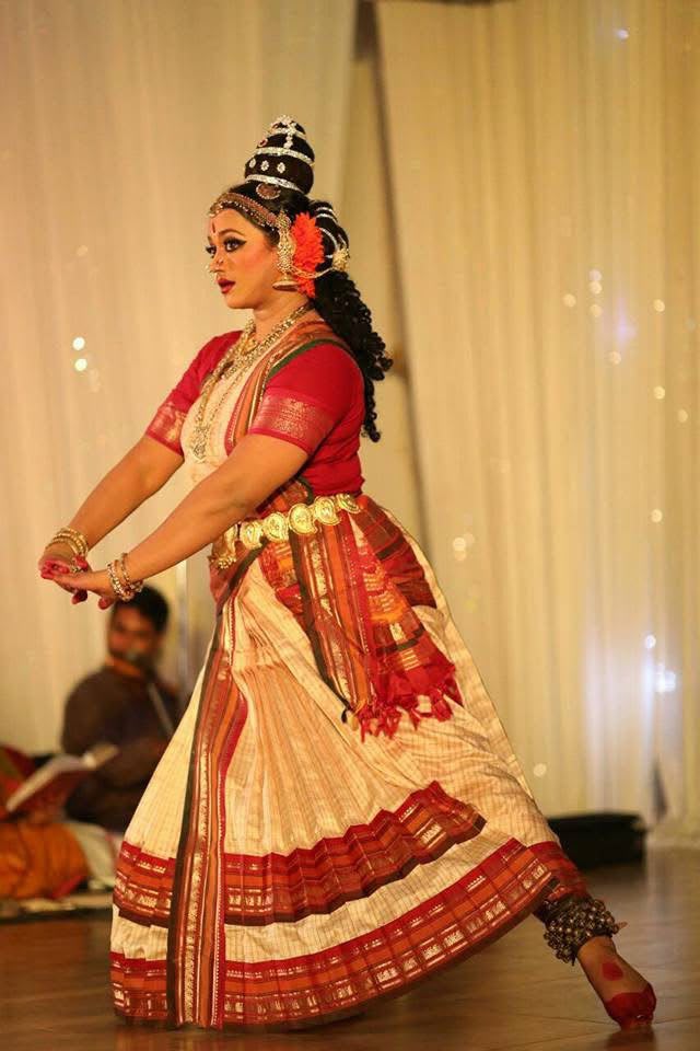 Dancer in red and cream costume in a dynamic Kuchipudi pose
