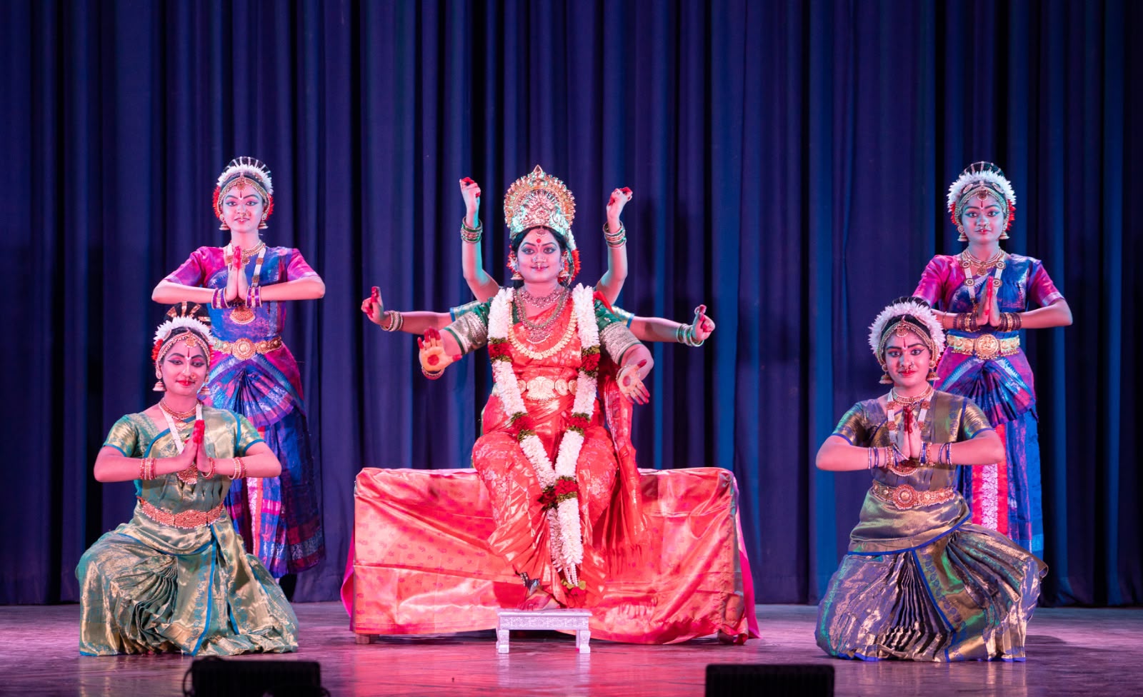 Group of five dancers on stage around a central deity figure
