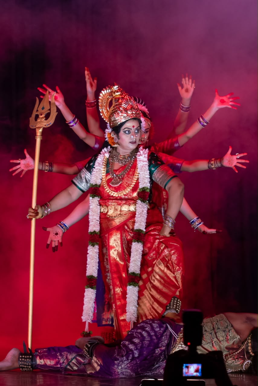 Solo dancer as a multi-armed goddess with trishul, dramatic stage fog