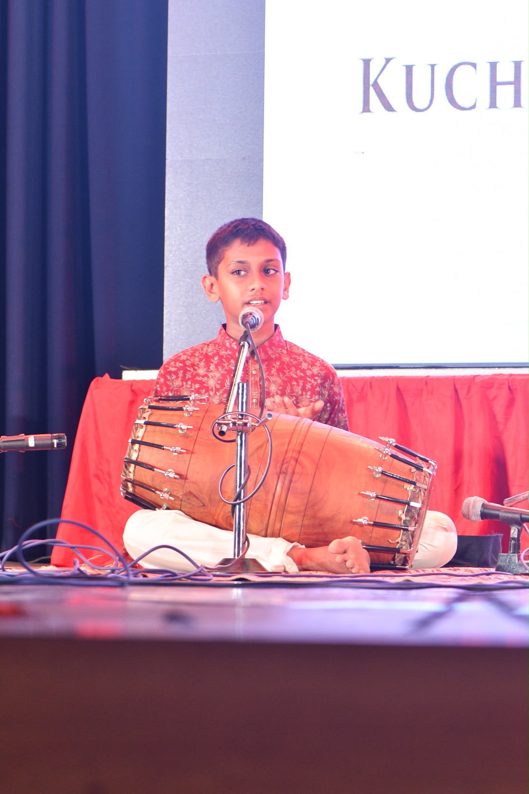 Young student playing the mridangam on stage