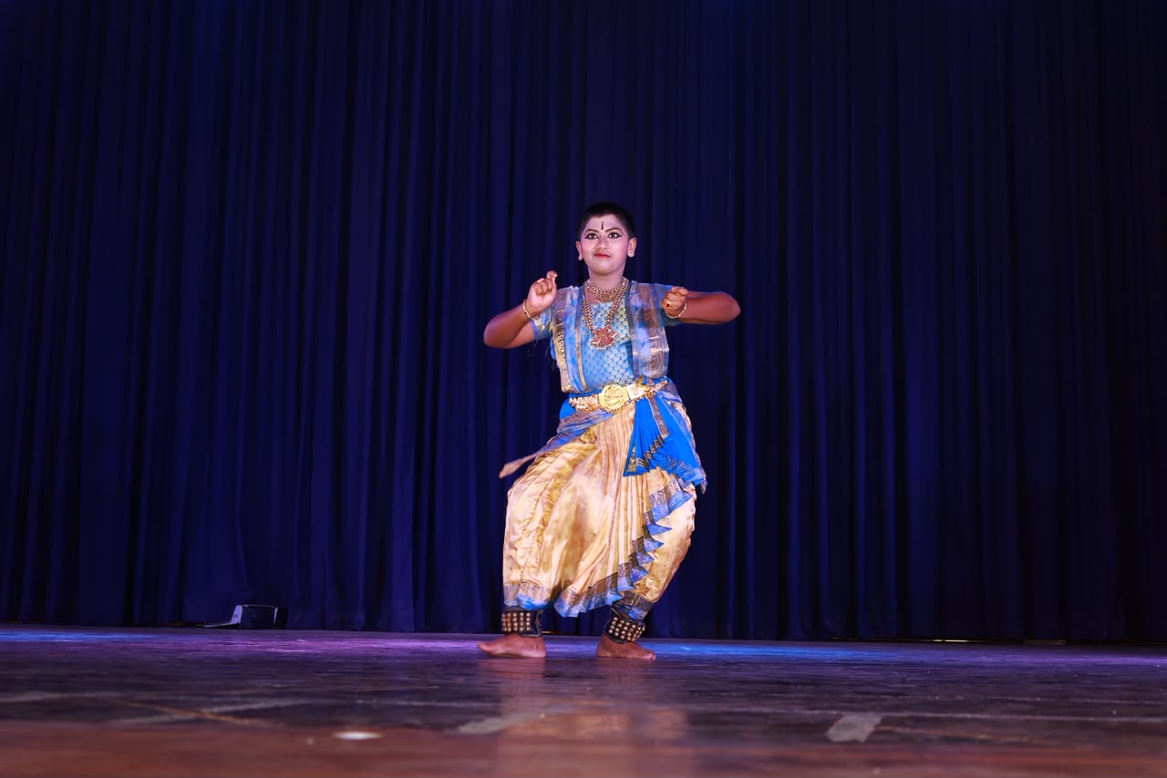 Young dancer in blue and gold costume mid-stance