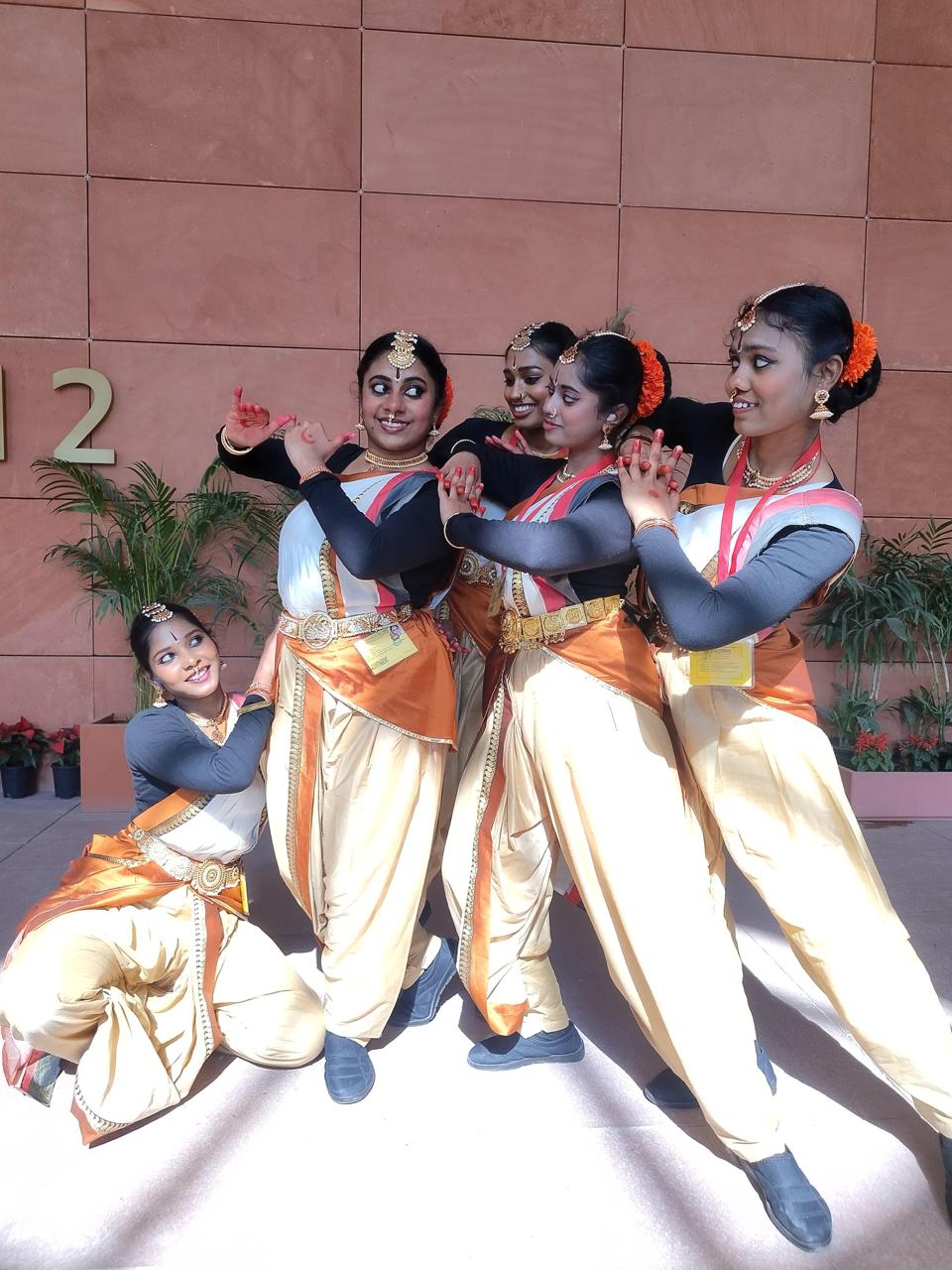 Five young performers in matching costumes posing playfully outdoors