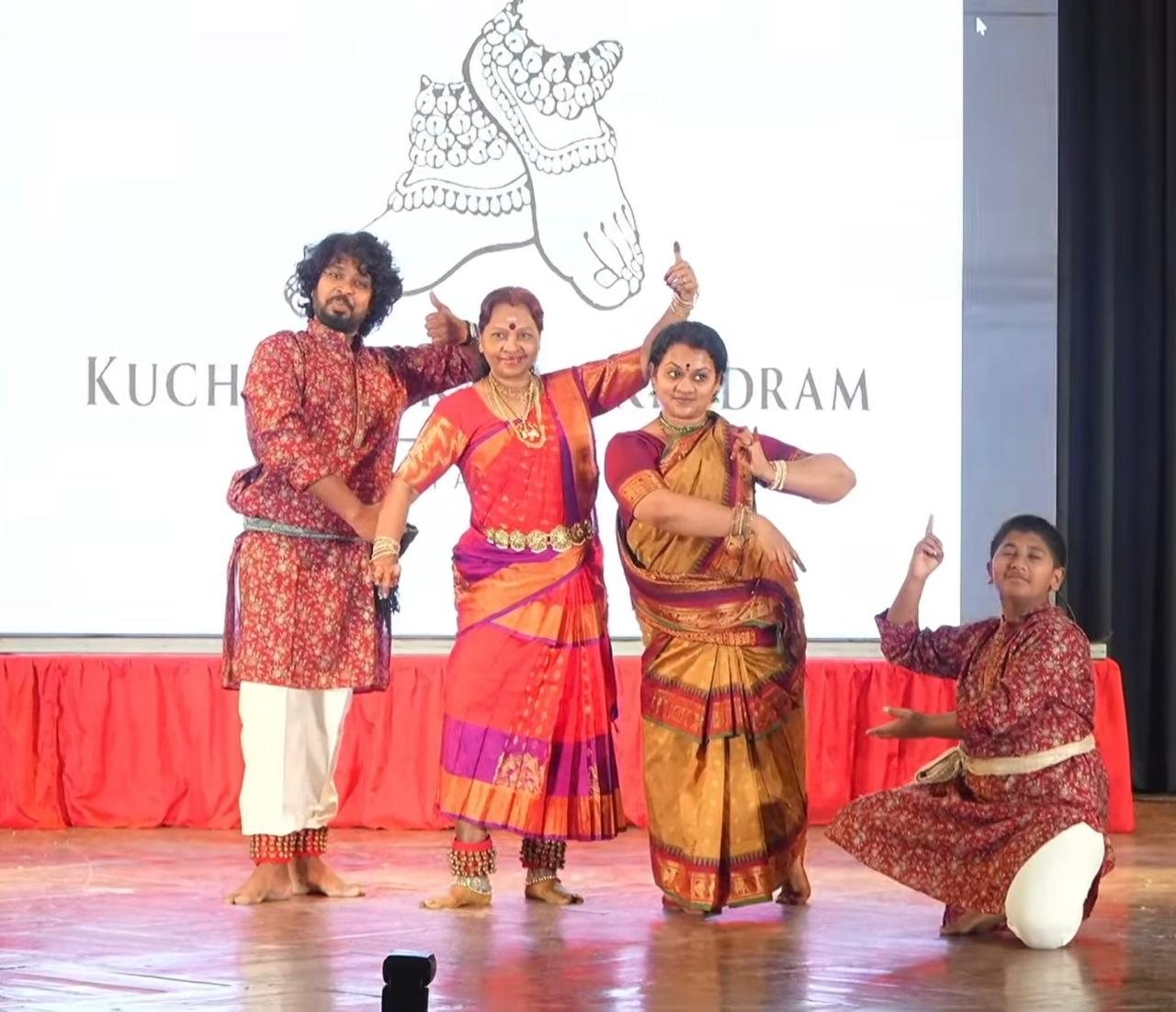 Founders and a young performer sharing a playful moment on stage in front of the Kuchipudi Kalaa Kendram backdrop